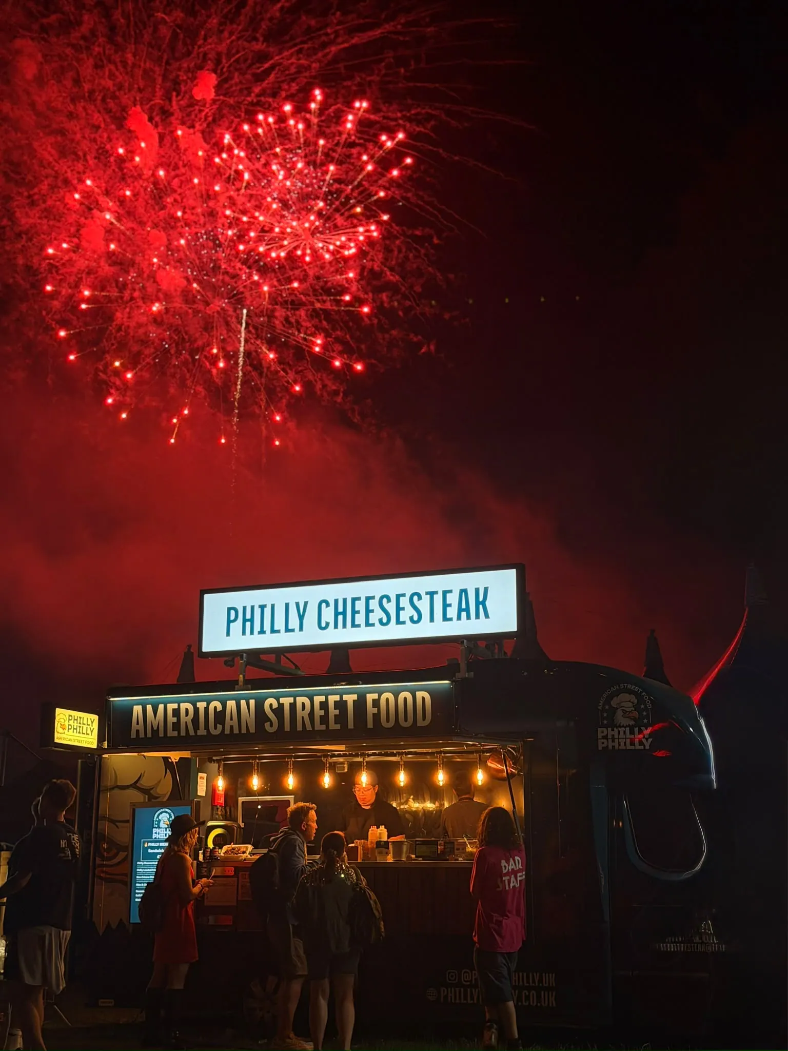 The Philly Philly food truck serving hot food under fireworks on a winter evening